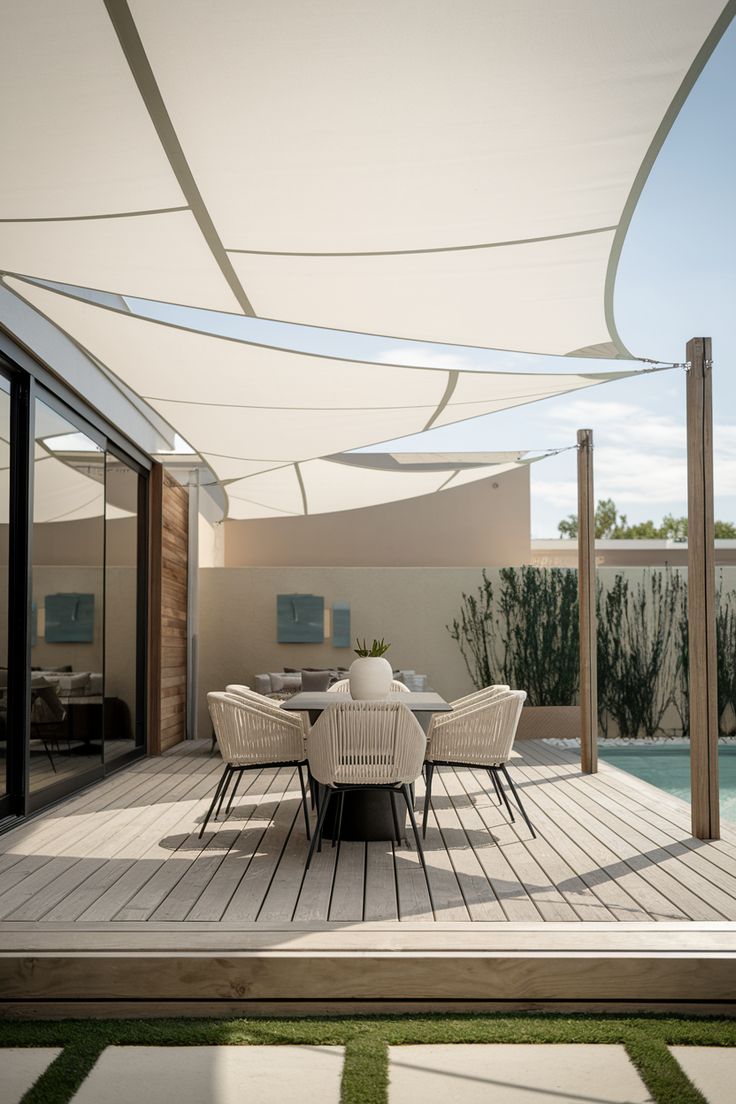 Dos toldos de vela triangulares sobre un patio de baldosas en Colina